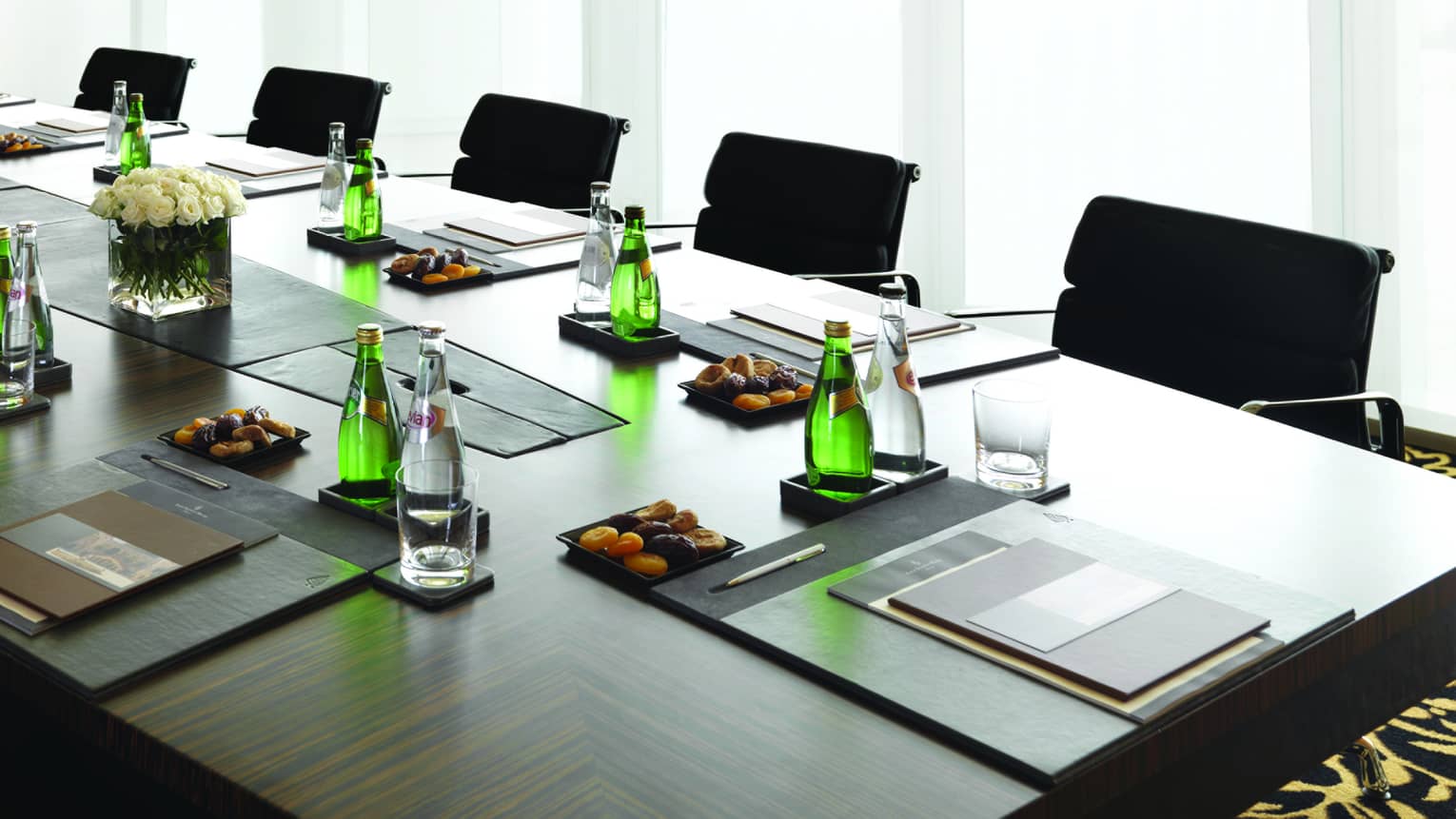Boardroom meeting table set with water, dried apricots, menus by sunny window