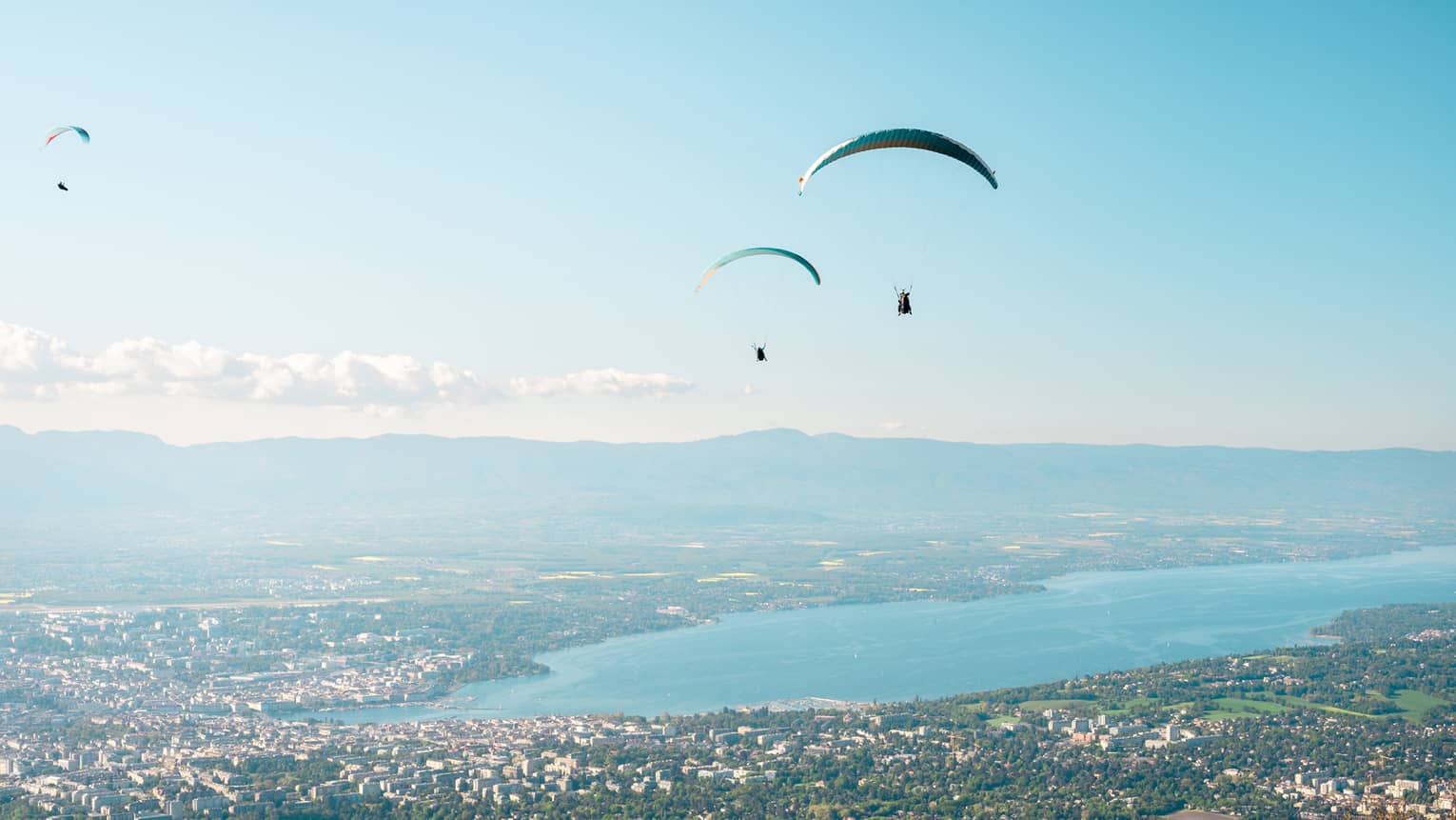 Three people paragliding near Lake Geneva