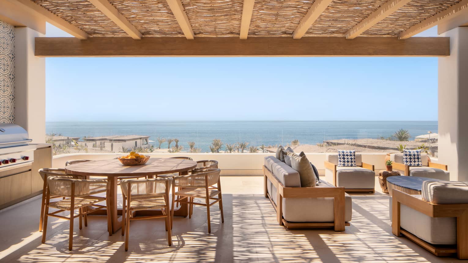 Covered terrace with lounge seating and a large round dining table and a view of the ocean from a luxury private villa at Four Seasons Resort and Residences Cabo San Lucas