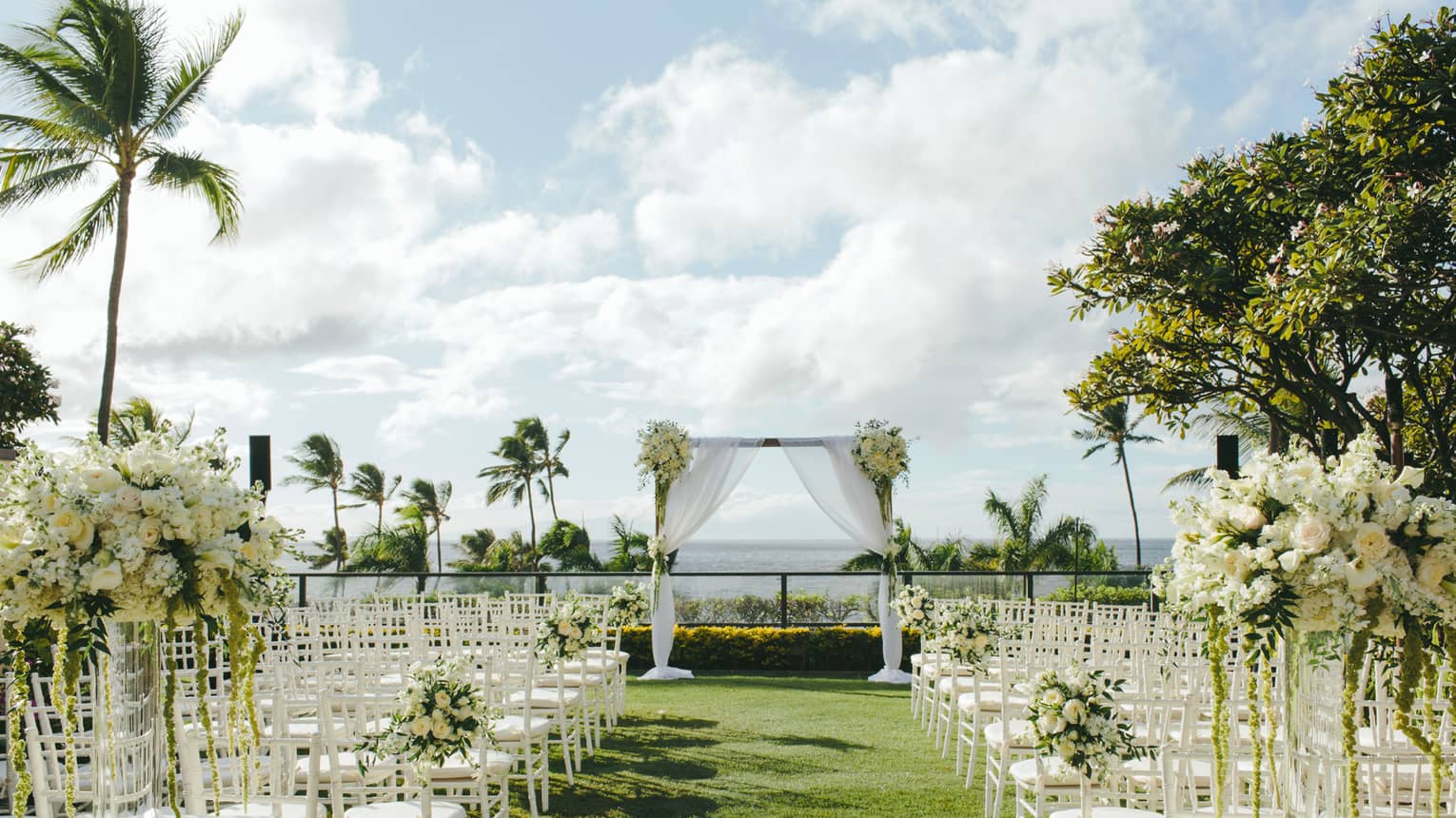 Outdoor wedding ceremony set up, rows of white chairs face altar on event lawn near ocean