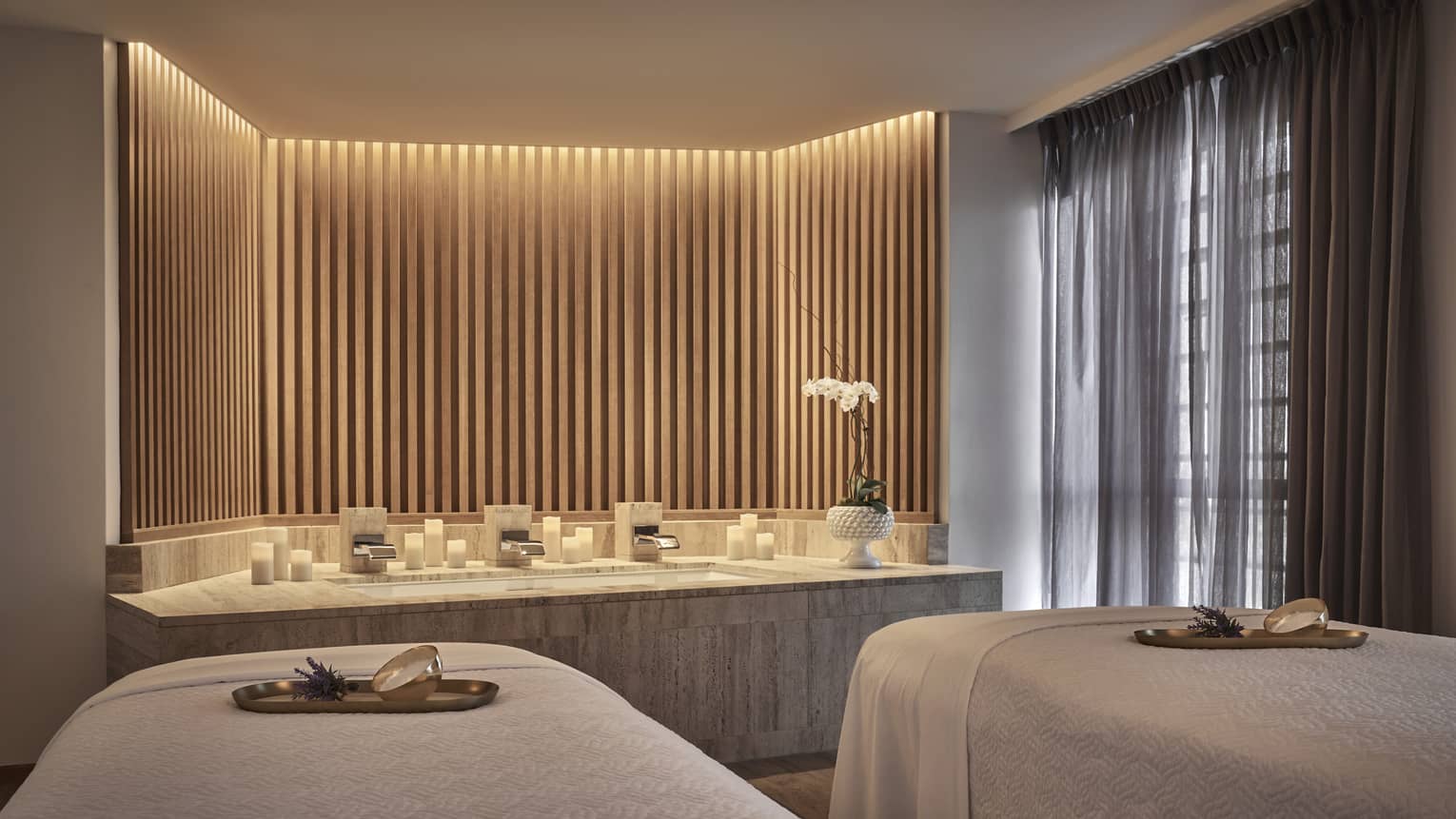 A spa treatment room with two spa beds and dim lighting