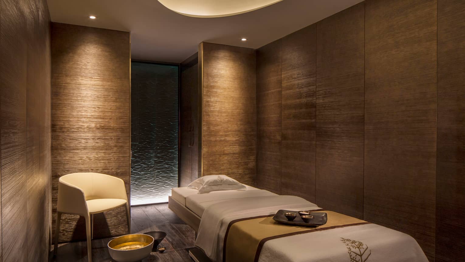 View of private massage room in spa and wellness centre, wood grain walls and low lighting