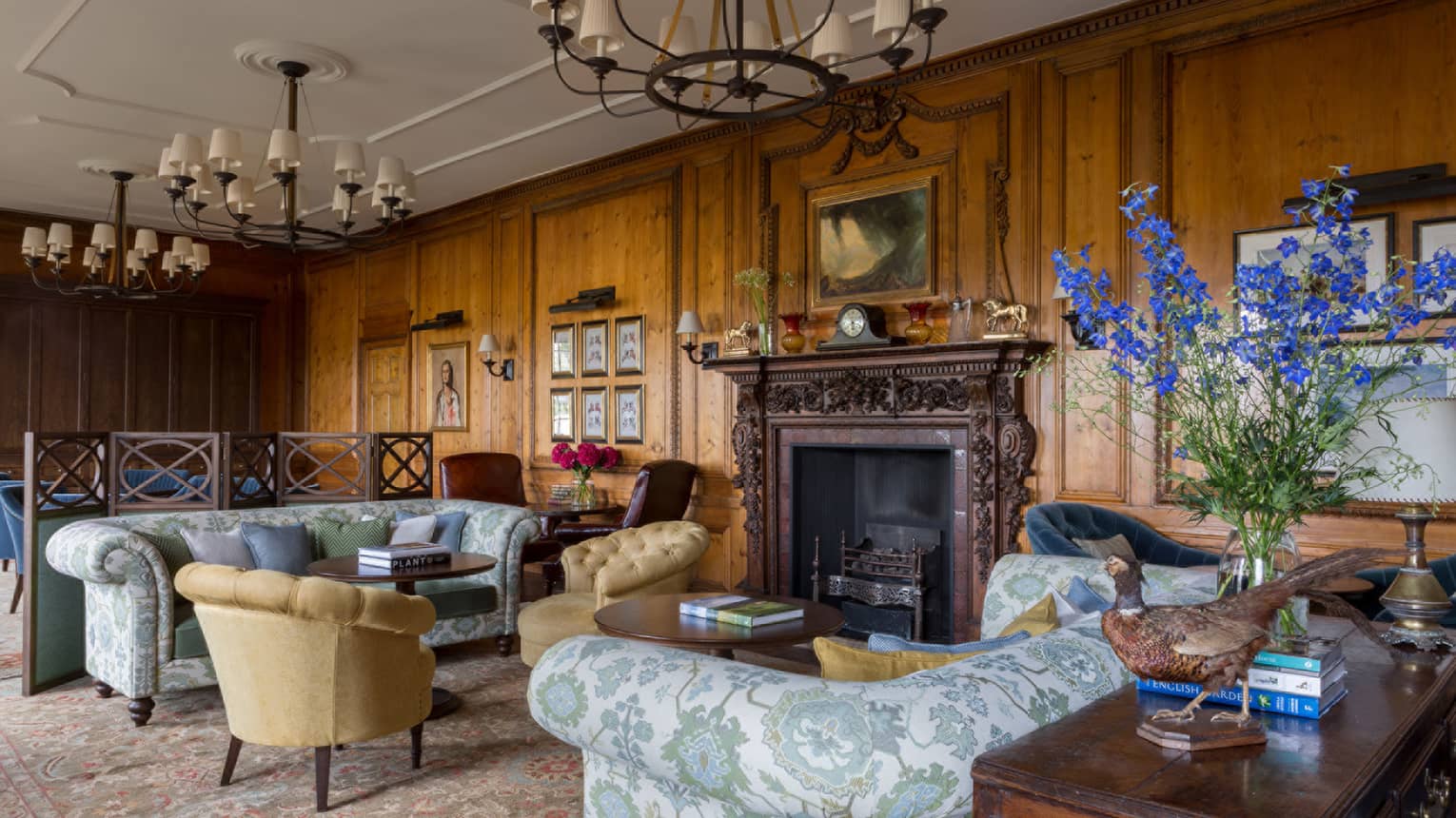 The Library, antique-style blue floral sofas, armchairs, rustic wood walls, soaring ceilings