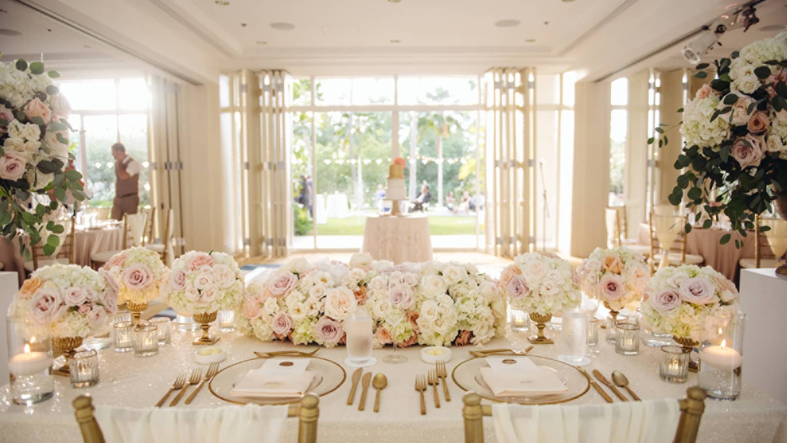 Elegant white and gold wedding banquet table setting with pink-and-white roses centrepiece