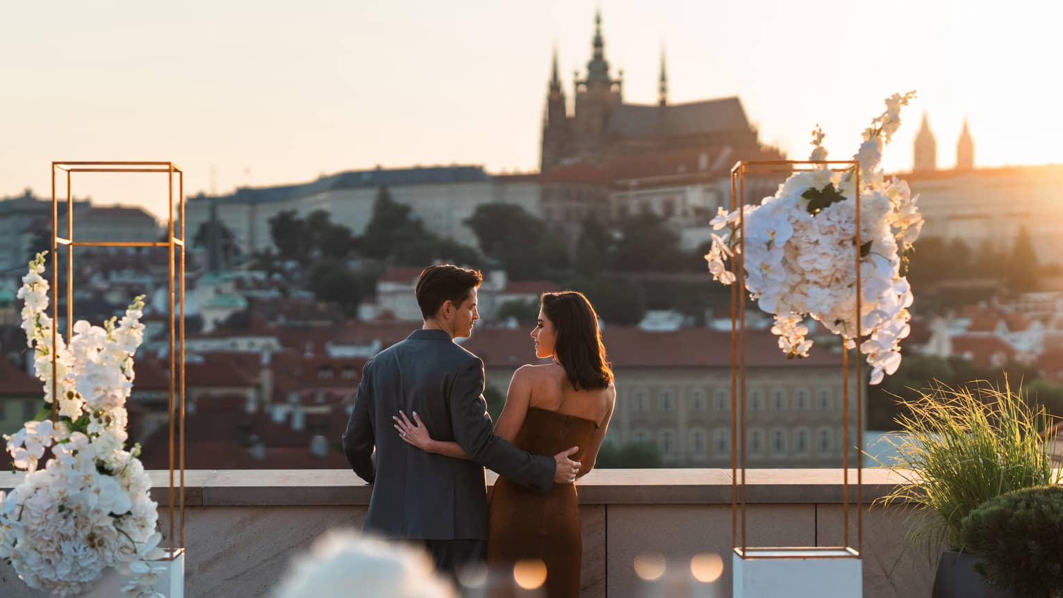 Couple embracing, looking at each other on terrace with view of the Prague Castle