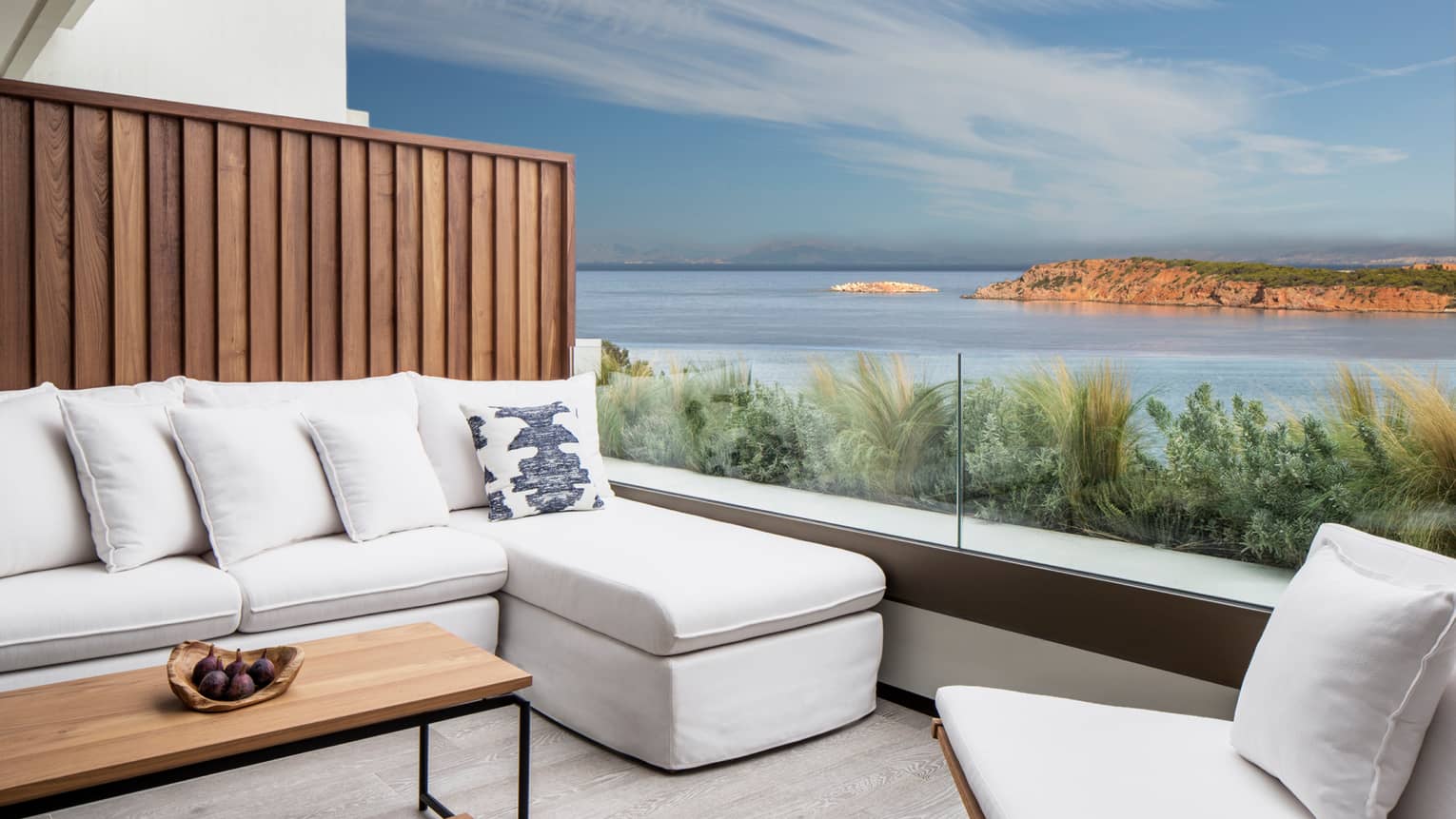 Outdoor terrace with white sofa and accent chair, rectangular coffee table, ocean views