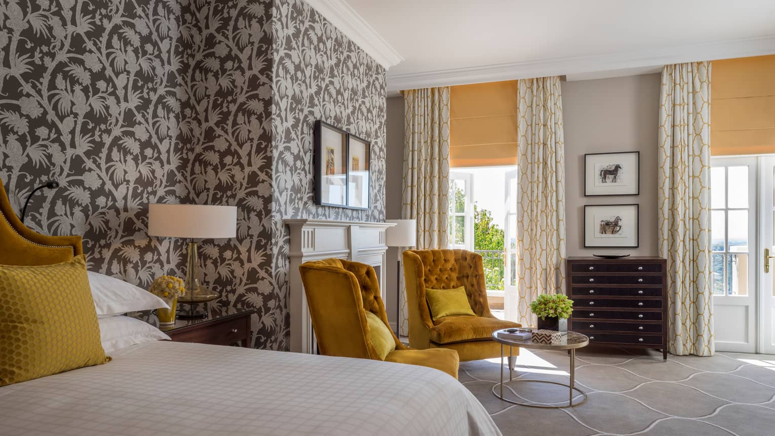Royal Suite bed, two gold tufted armchairs around small glass table, tropical wallpaper 