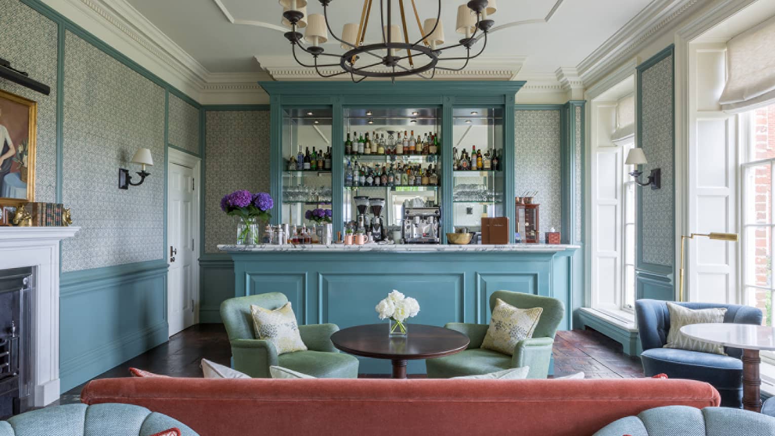 Library and Drawing Room Bar with rose-coloured sofa, lounge seating areas and stocked blue bar on back wall