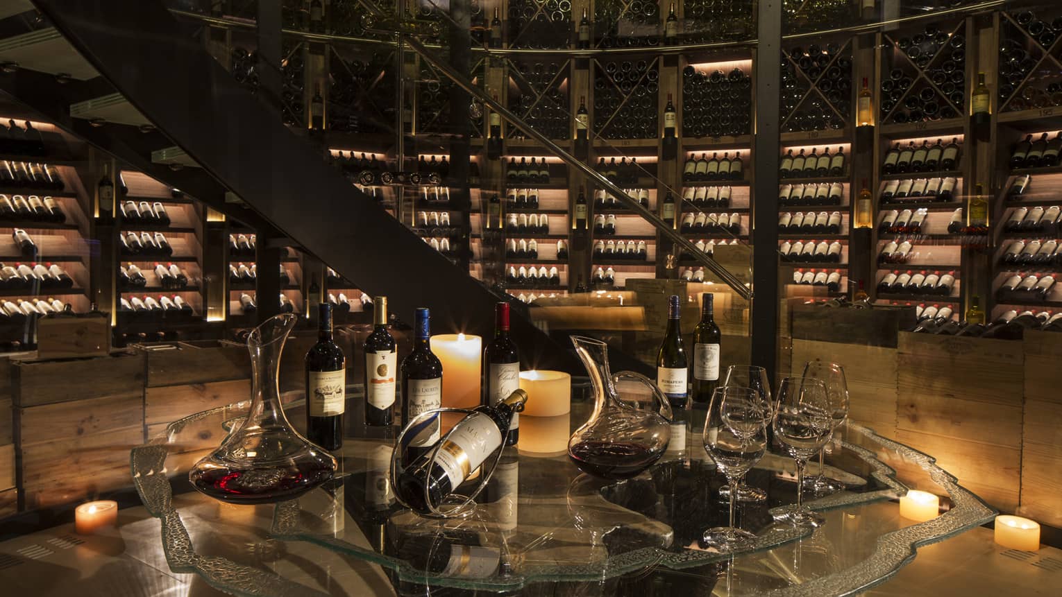 Bottles of wine are arranged for a tasting within an expansive, candlelit wine cellar