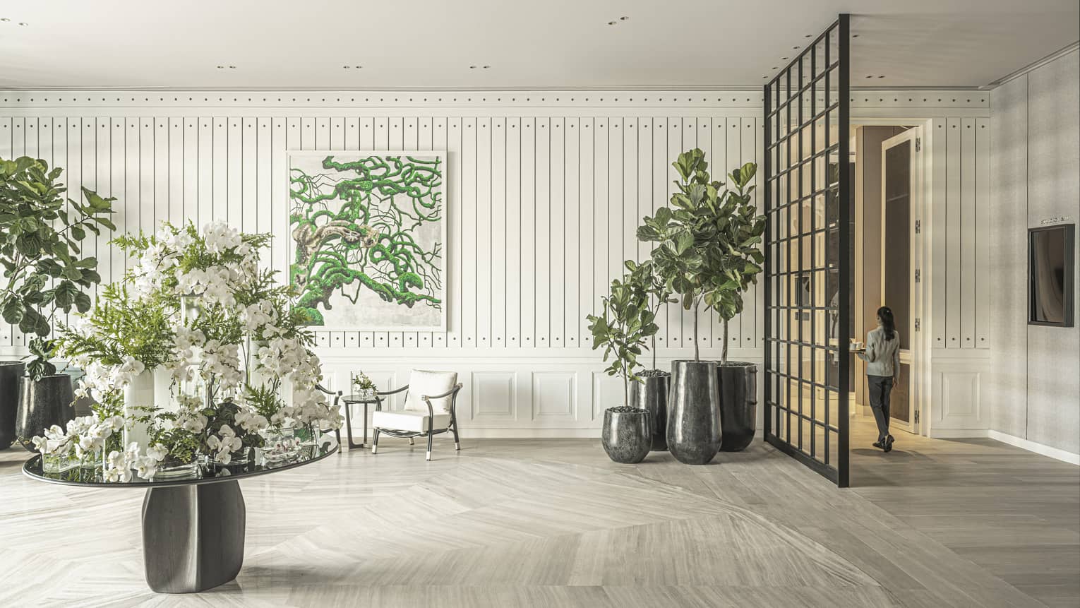 Studio I with ivory wooden floors, potted green foliage, center table with white floral arrangement