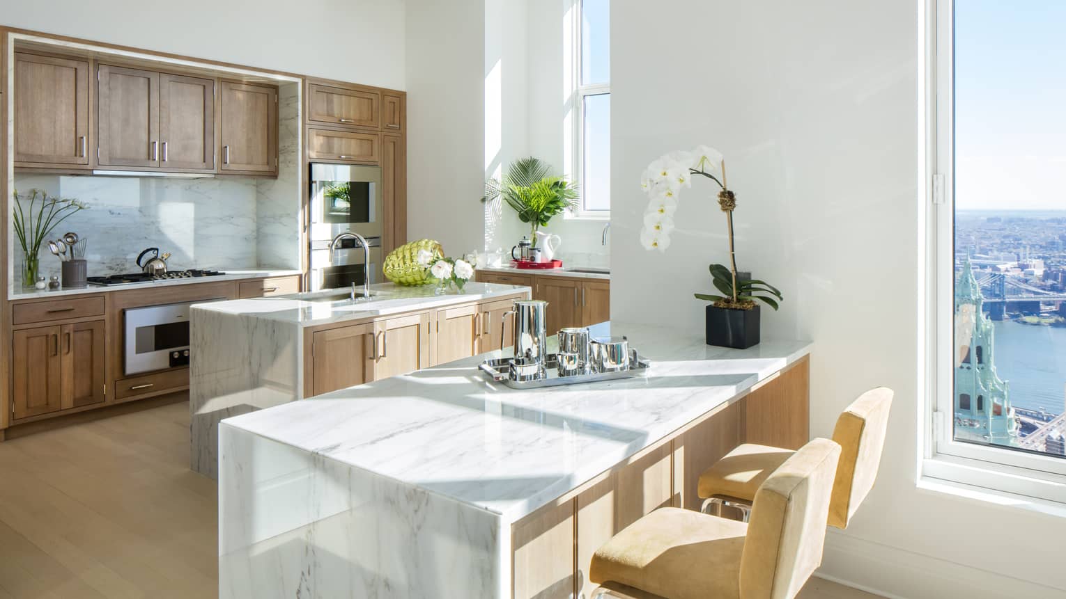 Kitchen island with Colorado White marble countertops and stools, solid oak cabinets, fresh white orchids