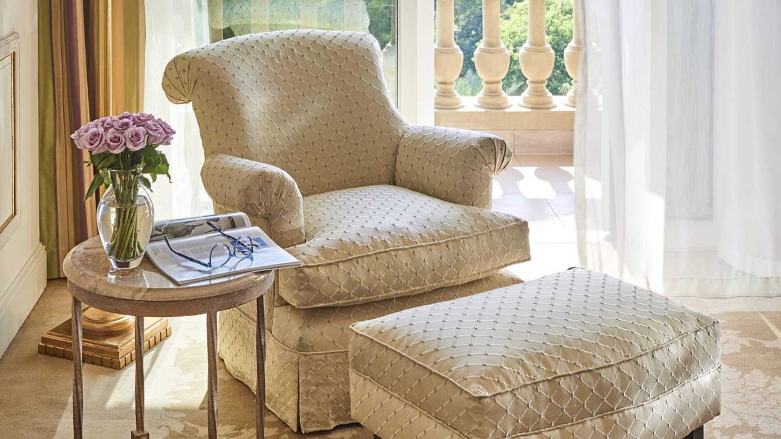 Beige and off white French-style chair with ottoman near window overlooking botanical gardens