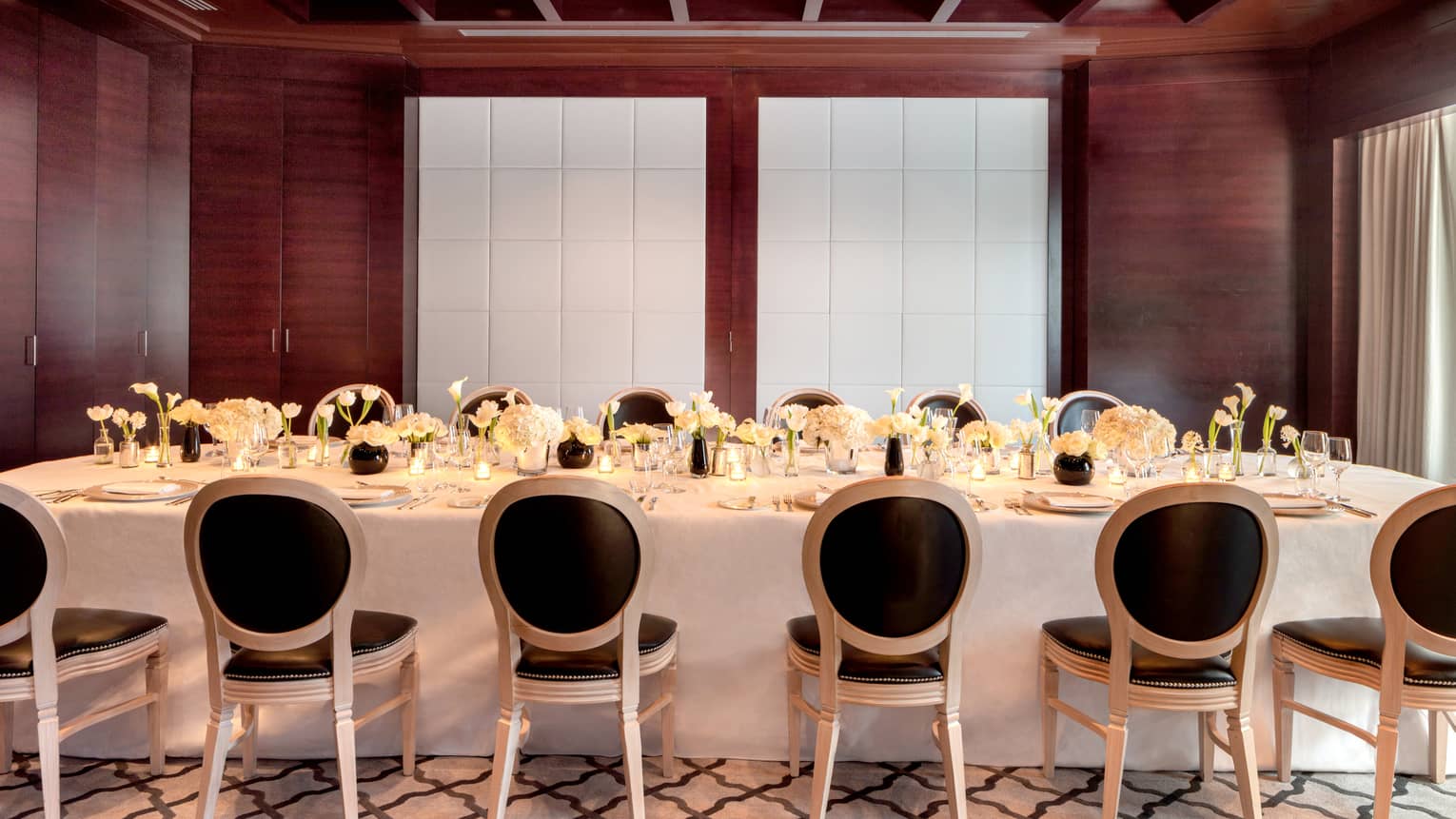 Meeting room set with white linens and black padded chairs 