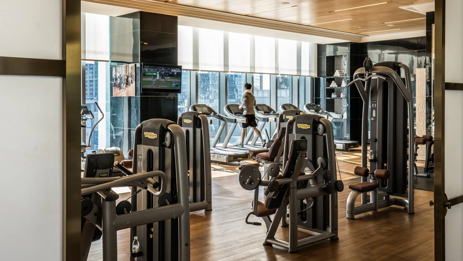 Man runs on treadmill in Fitness Centre by cardio machines, window