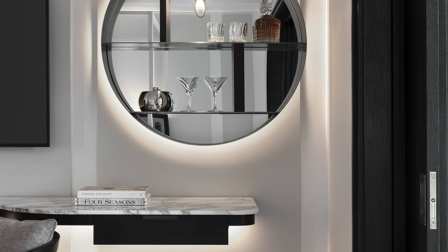In-room bar with round modern mirror and cocktail glasses on shelves