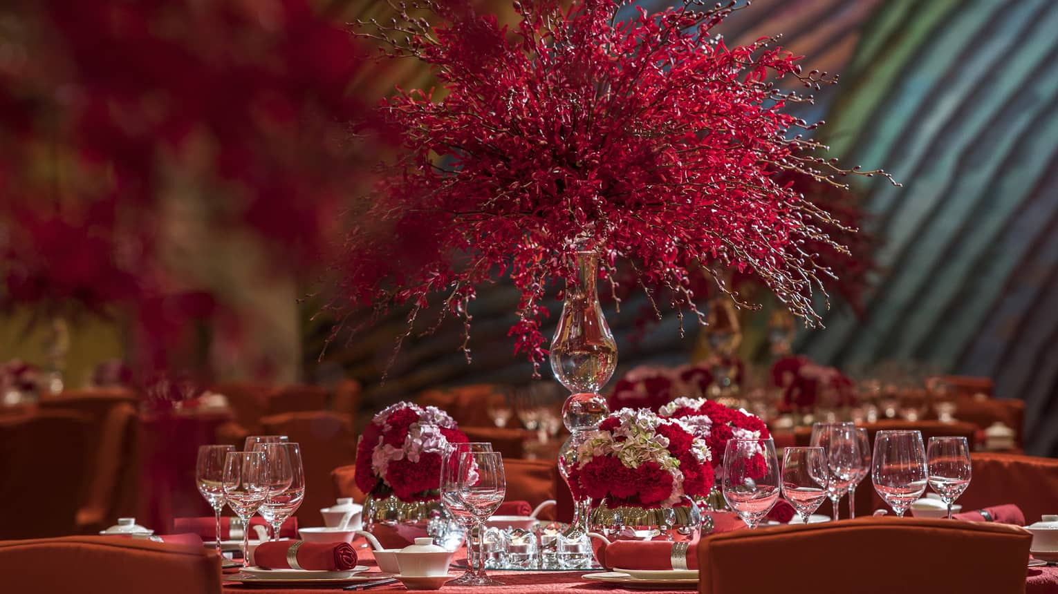 Close-up of banquet dining table with red tablecloth, red and white flower displays