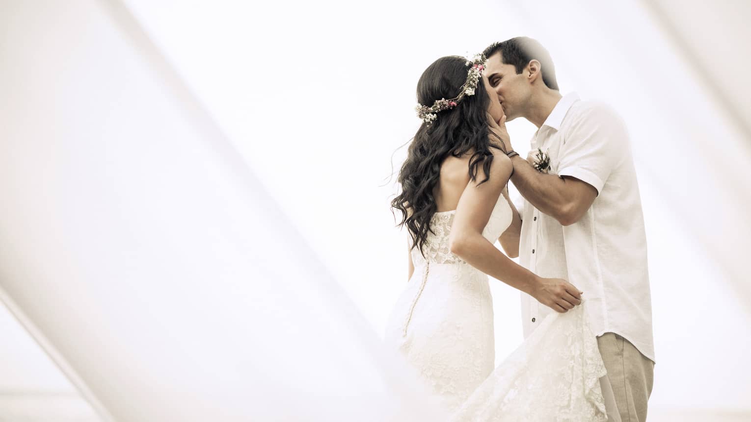 Bride and groom wearing white kiss 