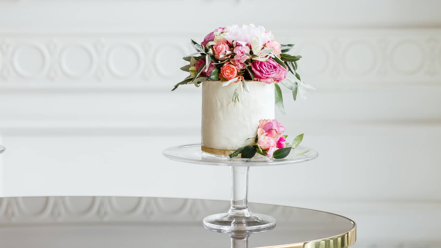 Elegant small white wedding cake topped with fresh pink and white roses 