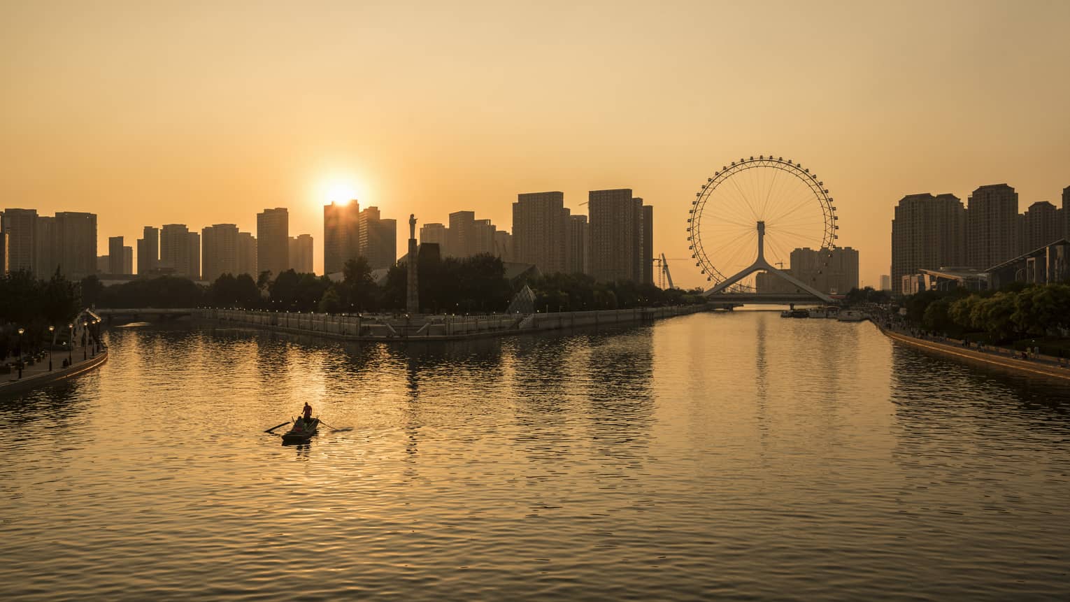 Silhouette of people in rowboat under Tianjin skyline, Eye ferris wheel at sunset