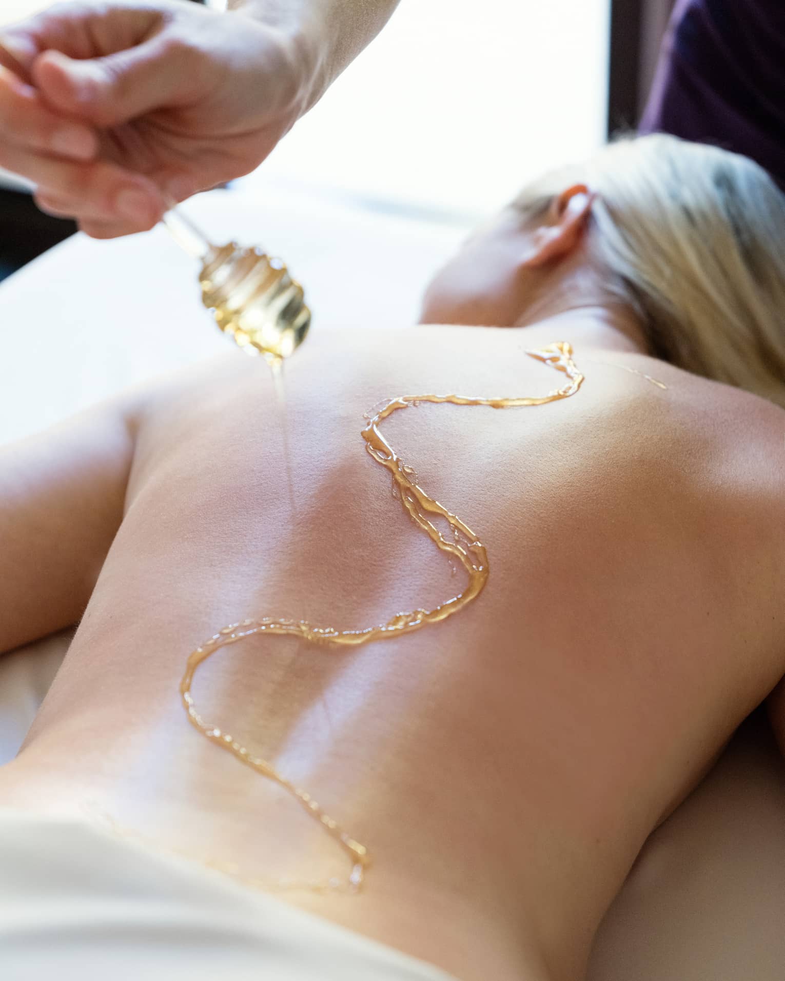 A woman receiving a massage using honey.