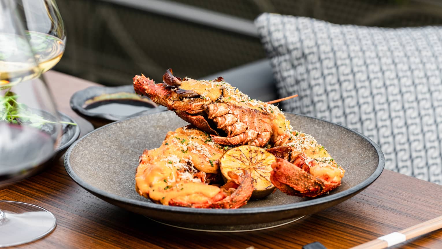 Spiny Lobster Thermidor on brown ceramic dish set on a wooden table with chopsticks
