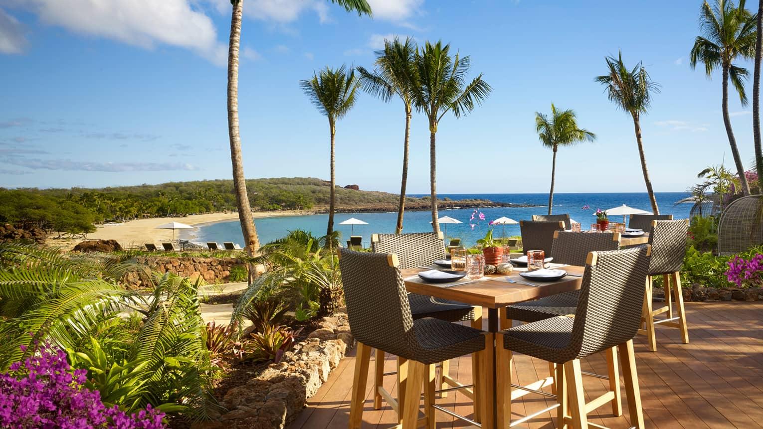 Malibu Farm Bar dining table, chairs on sunny patio overlooking beach, ocean