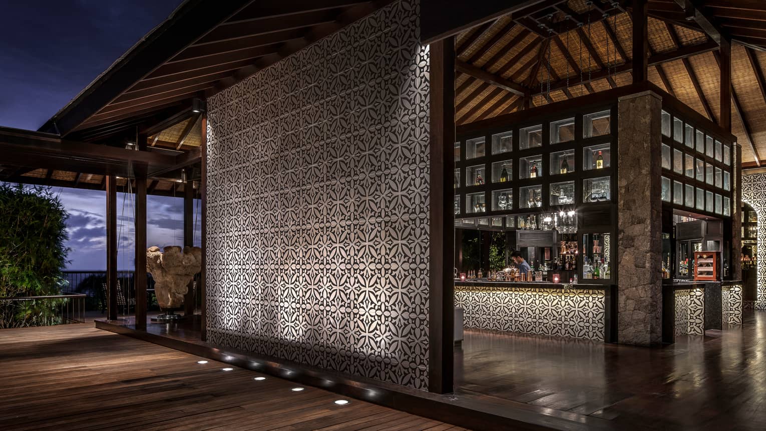 Bar interior, showing mosaic wall and mosaic lined bar with bartender and evening views out window