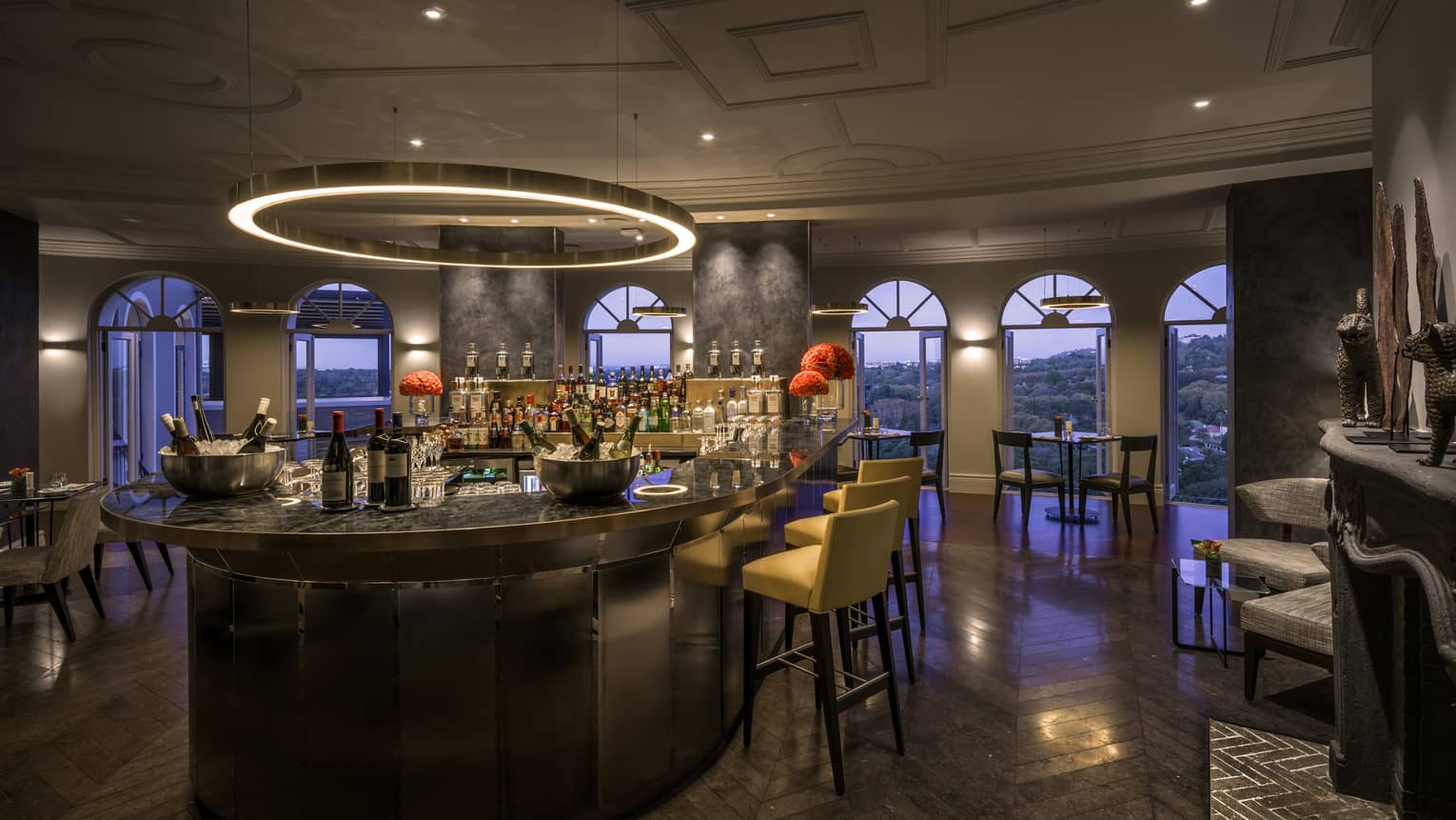 Dimly lit bar with circular overhead light and lounge area with outdoor view