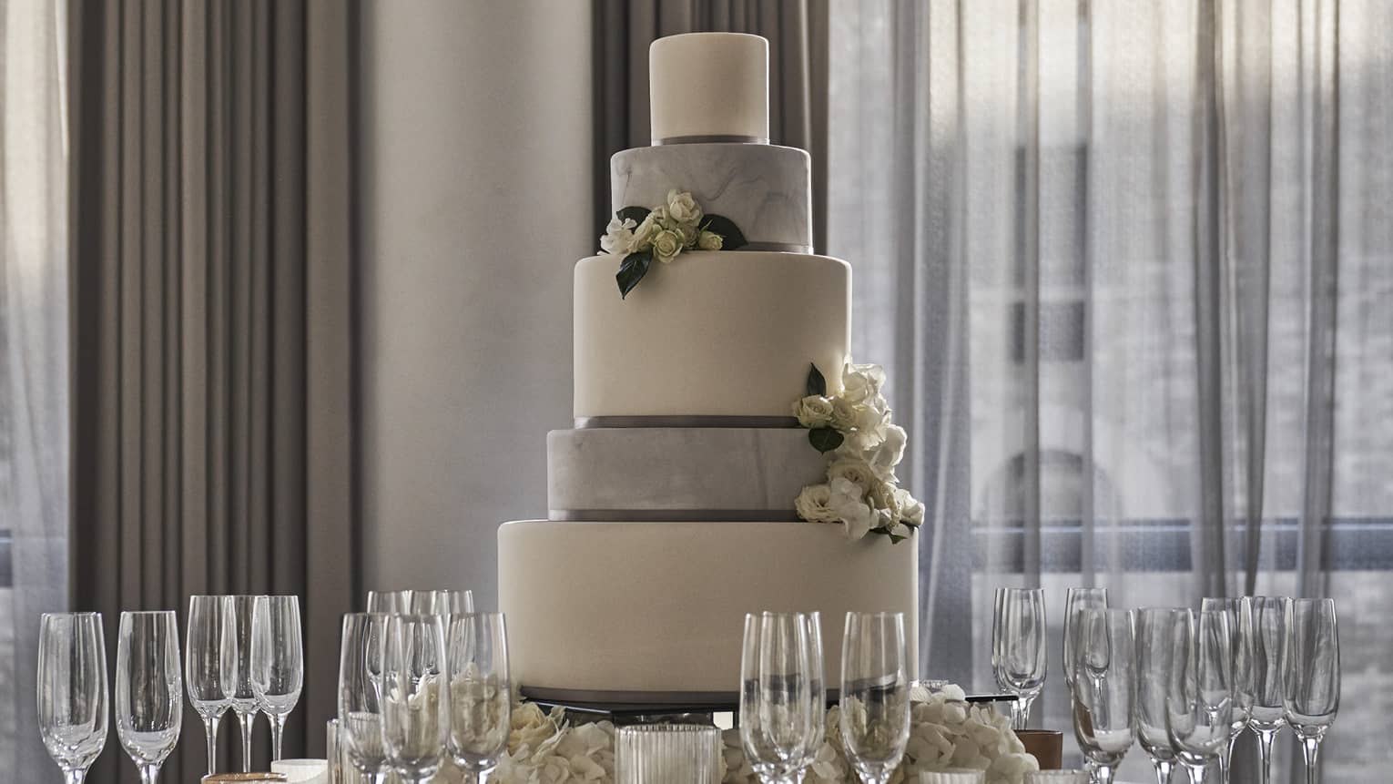 Tiered wedding cake on round banquet table with Champagne glasses