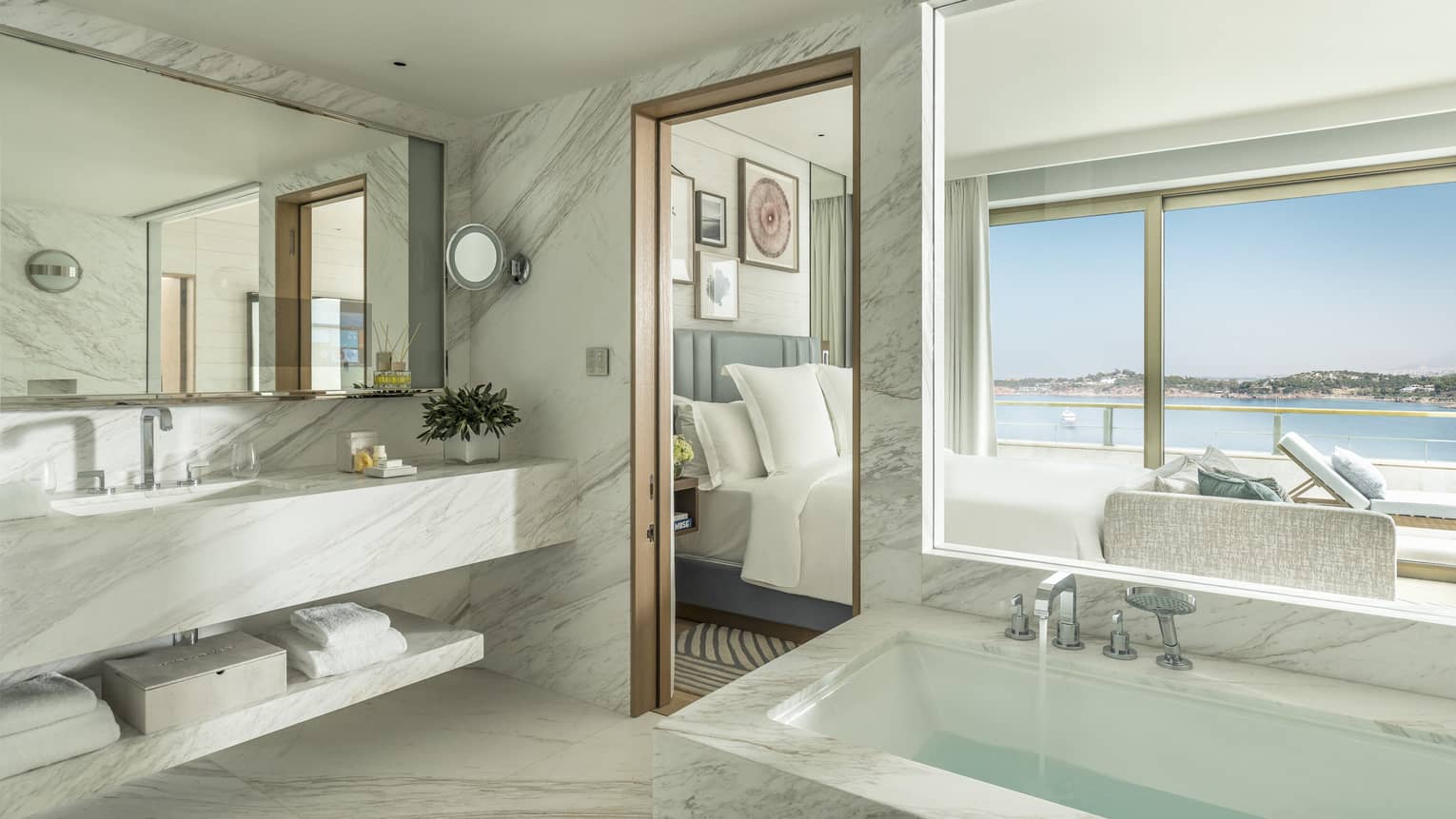 Arion One Bedroom Suite Bathroom with marbled double vanity, full-width mirror, large rectangular marbled tub, ocean views