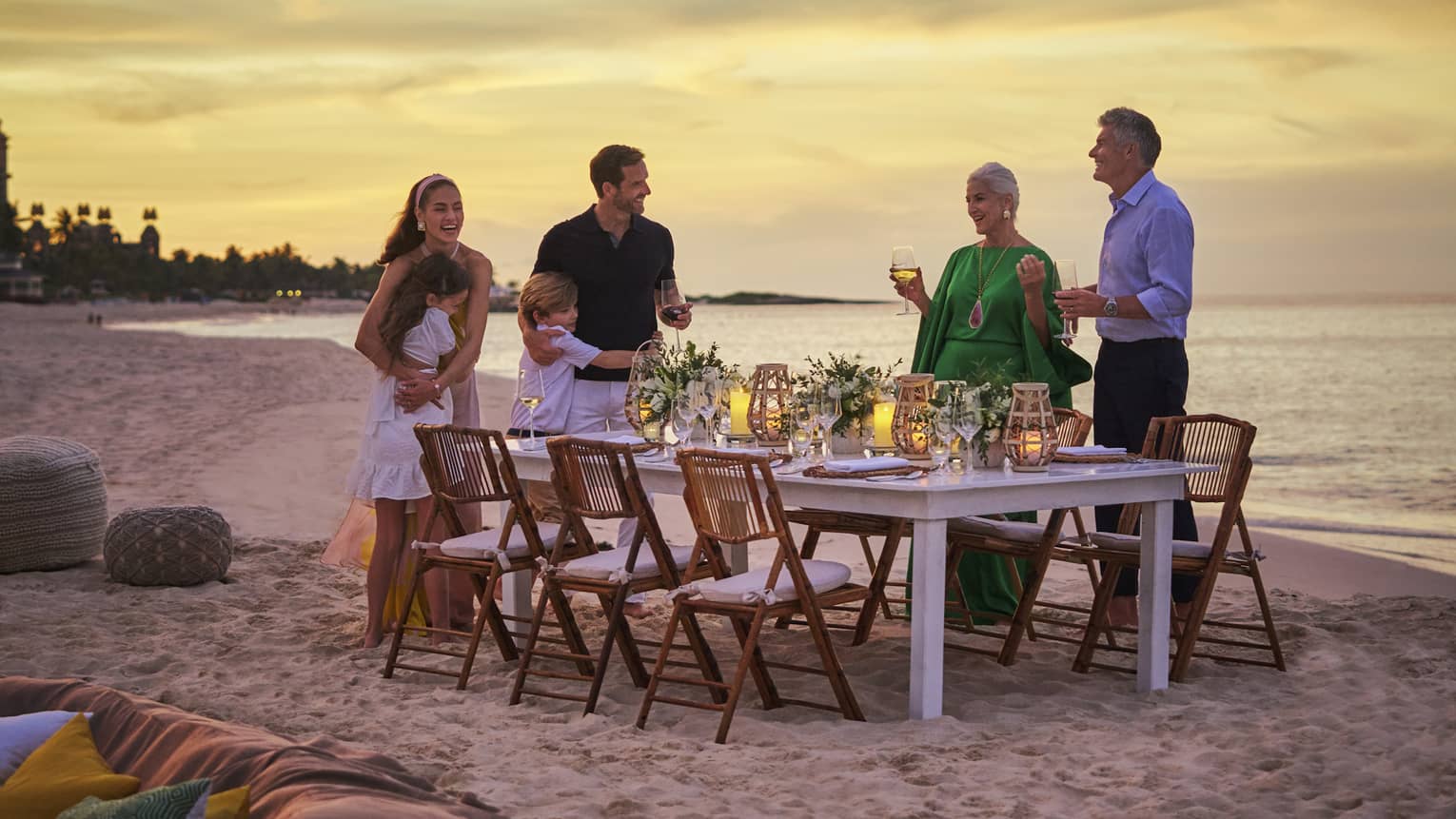 Family standing around dining table on the beach.