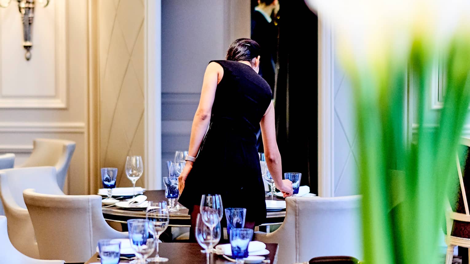 Back of woman wearing black dress standing over Le George dining table