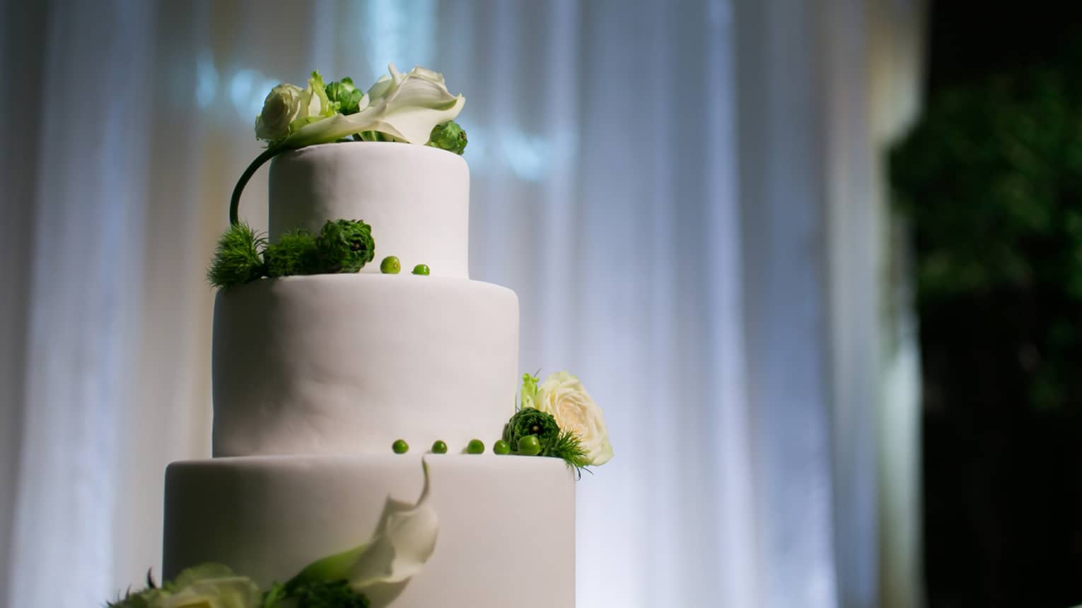 Tiered white wedding cake decorated with white and green flowers