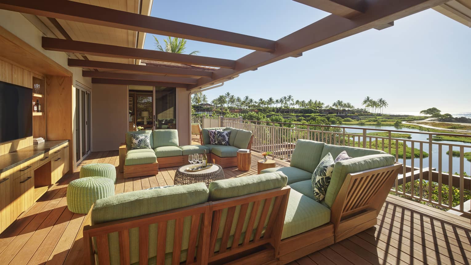 Private wooden deck, lounge sofas with green cushions, tropical view