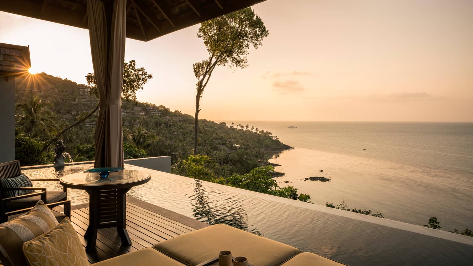 One-bedroom pool villa patio chair, infinity pool overlooking mountain, ocean at sunset