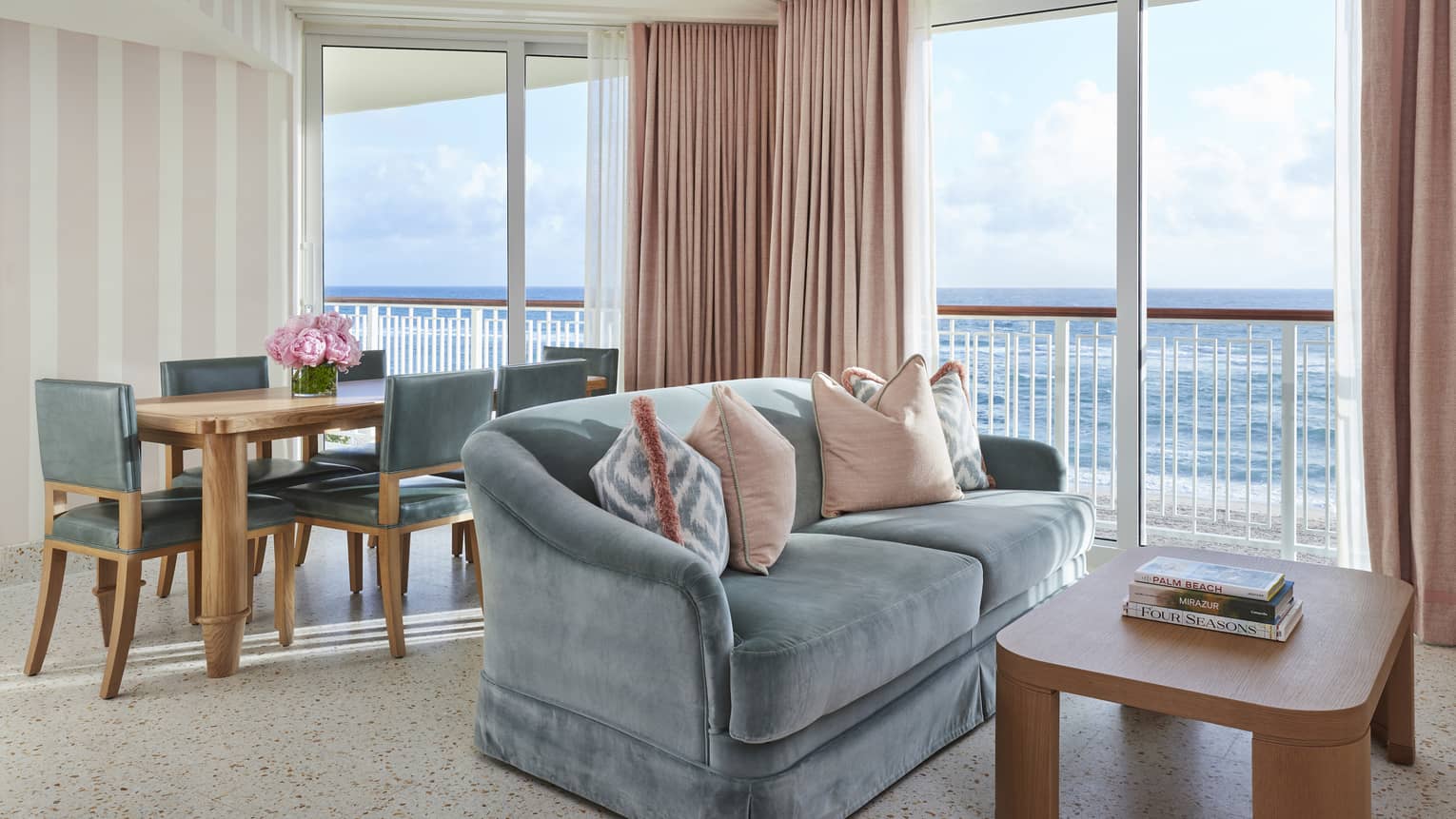 Dining table and two-seat sofa in a hotel suite's living room, with ocean views