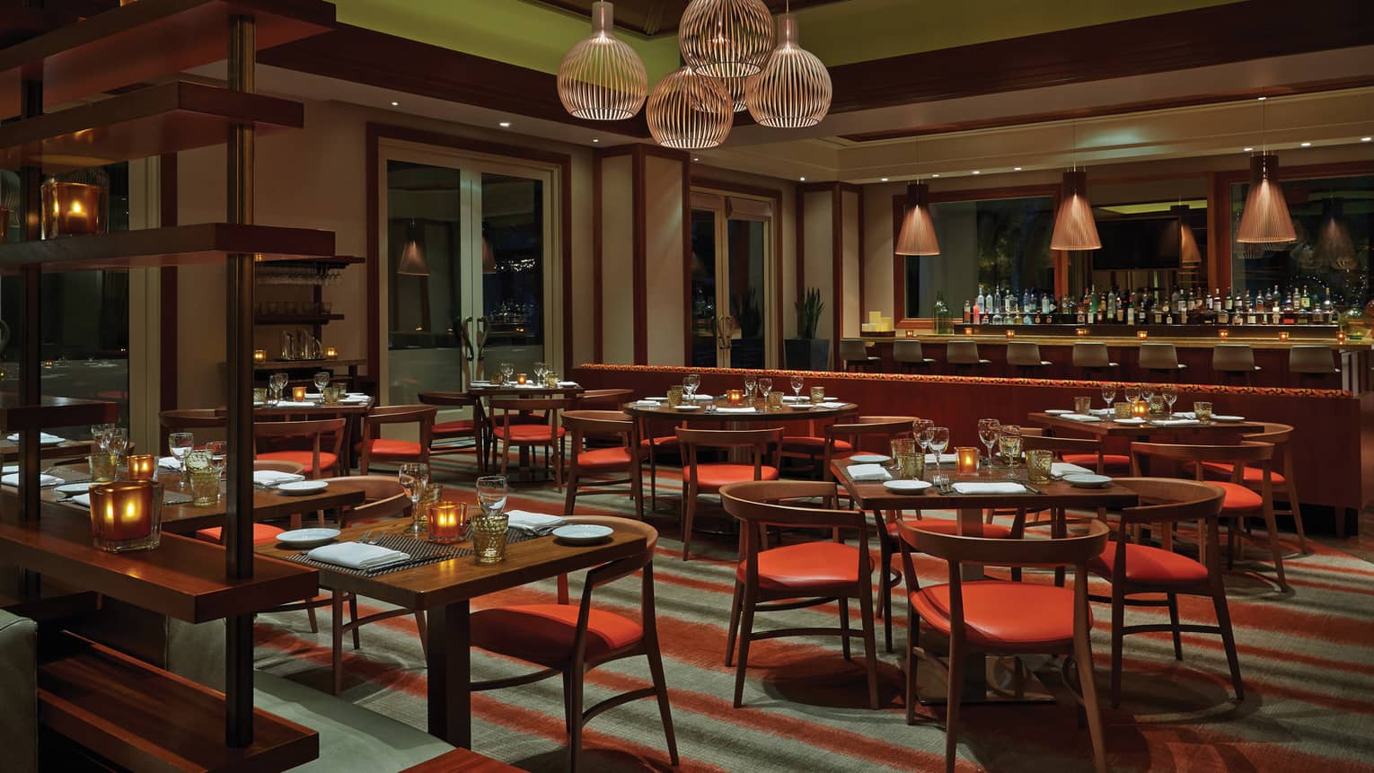 Veranda dining room with retro-style tables, chairs with red seats, hanging lights