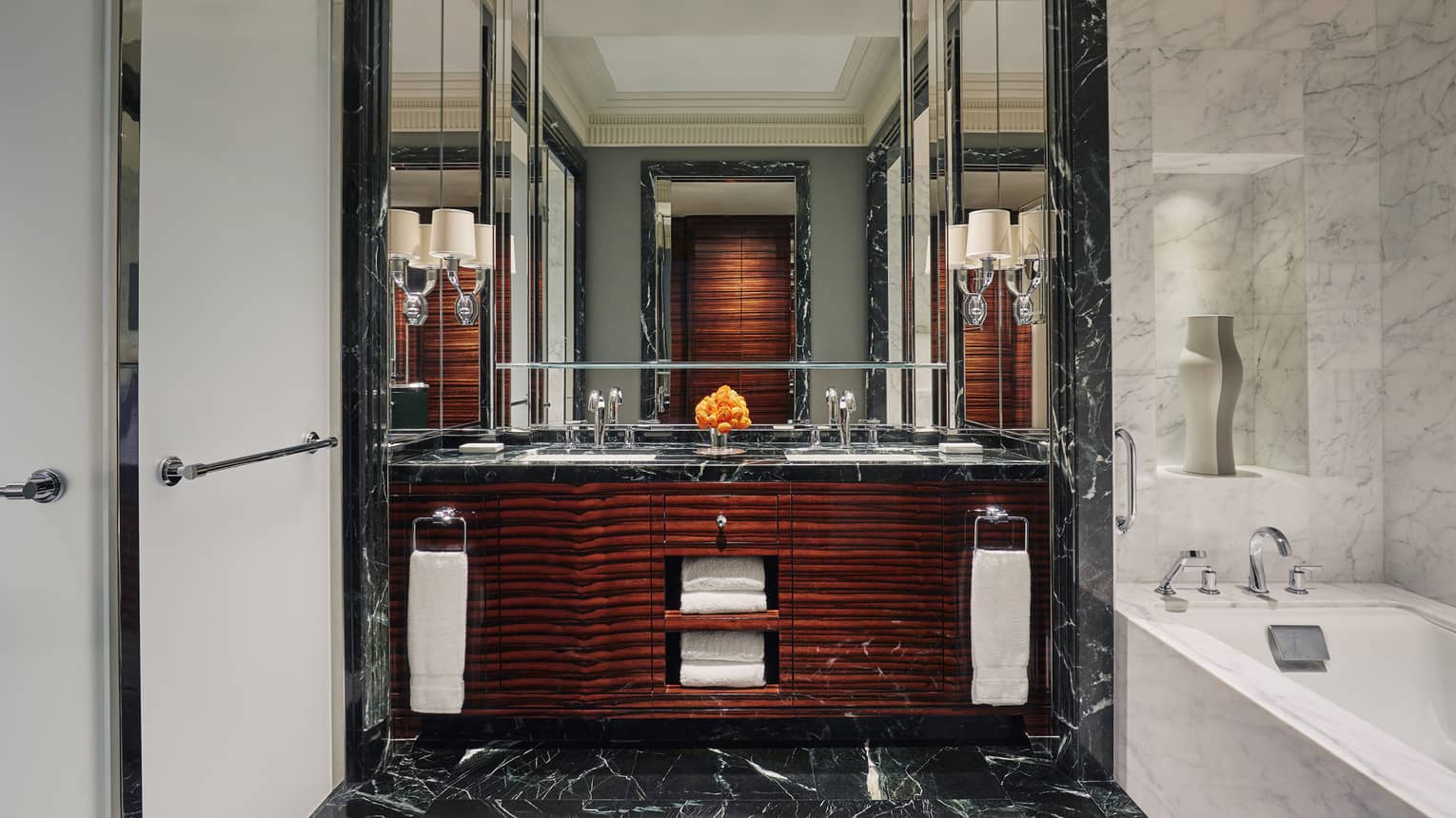 Large bathroom with black marble for the floor can vanity counter, dark wood veneer on the vanity cabinets and a white marble bathtub
