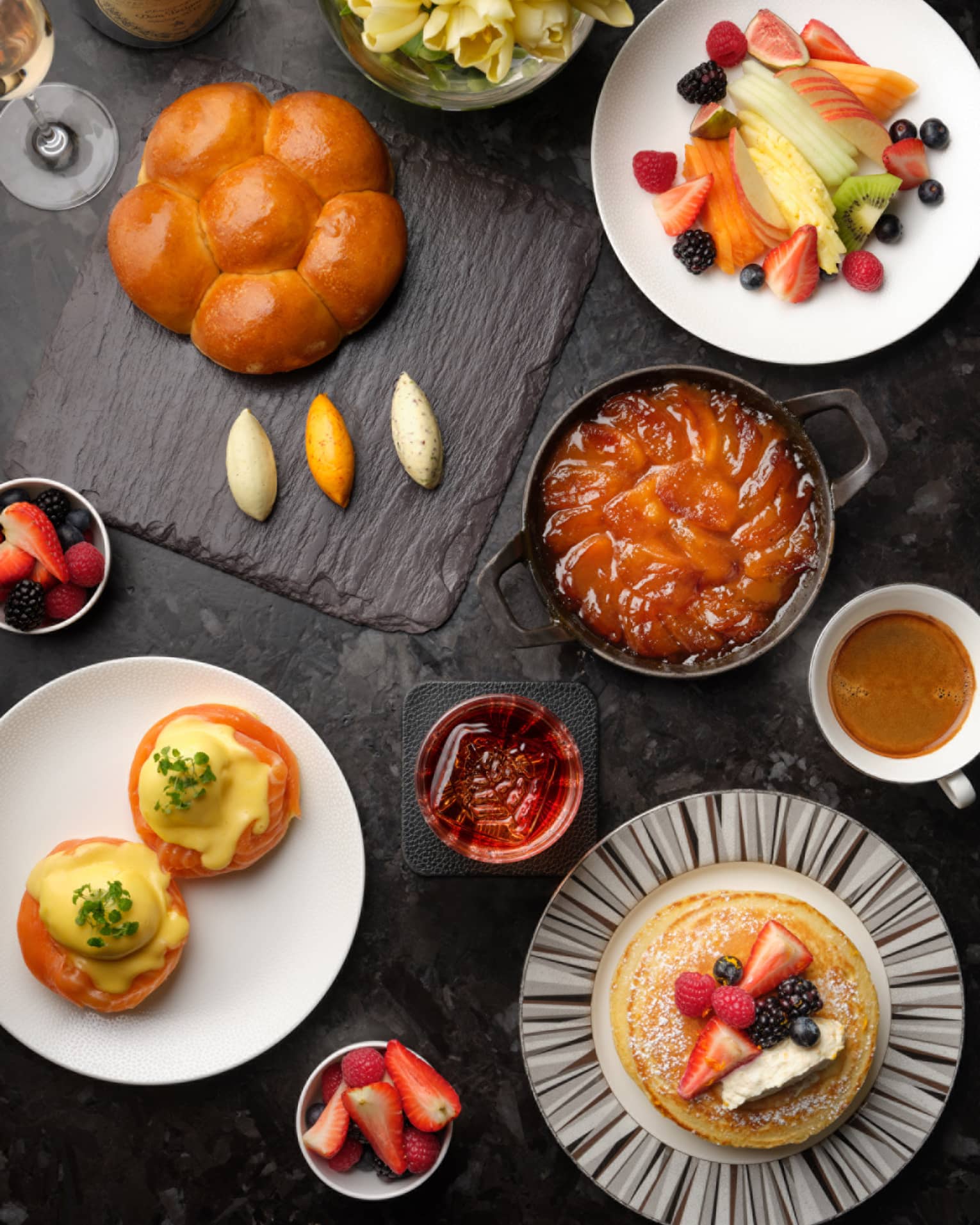 Brunch plates with pastries, fruits, pancakes and coffees on black table