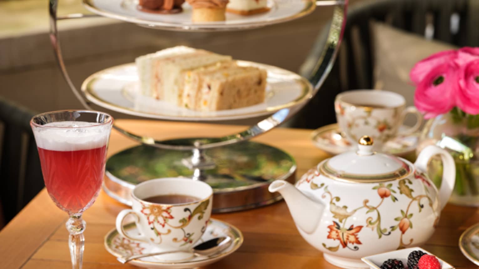 Afternoon tea service with floral teapot, cups, desserts on tiered tray