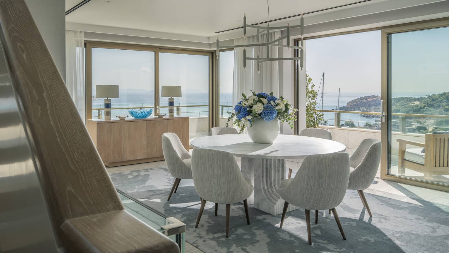 Arion Riviera Suite dining area with round table, white bucket chairs, panoramic ocean views