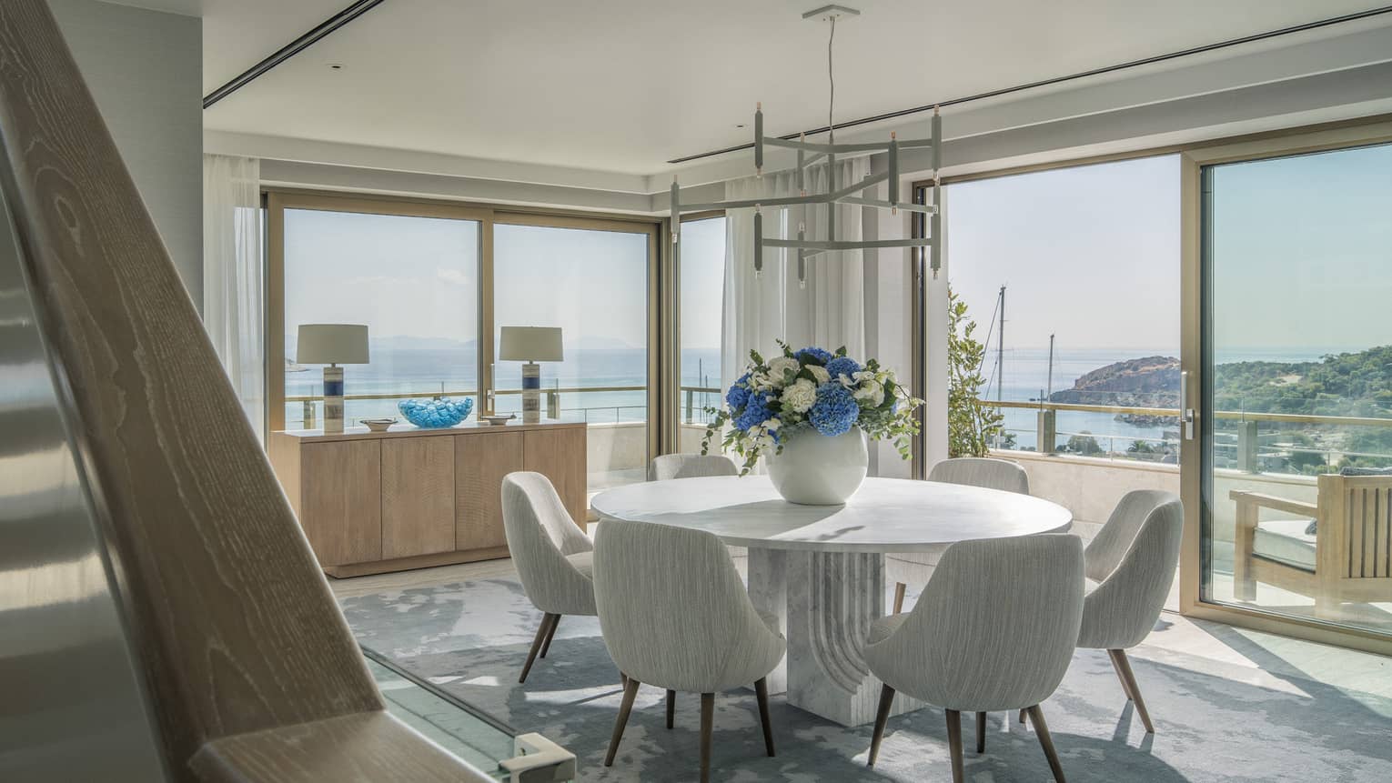 Arion Riviera Suite dining area with round table, white bucket chairs, panoramic ocean views