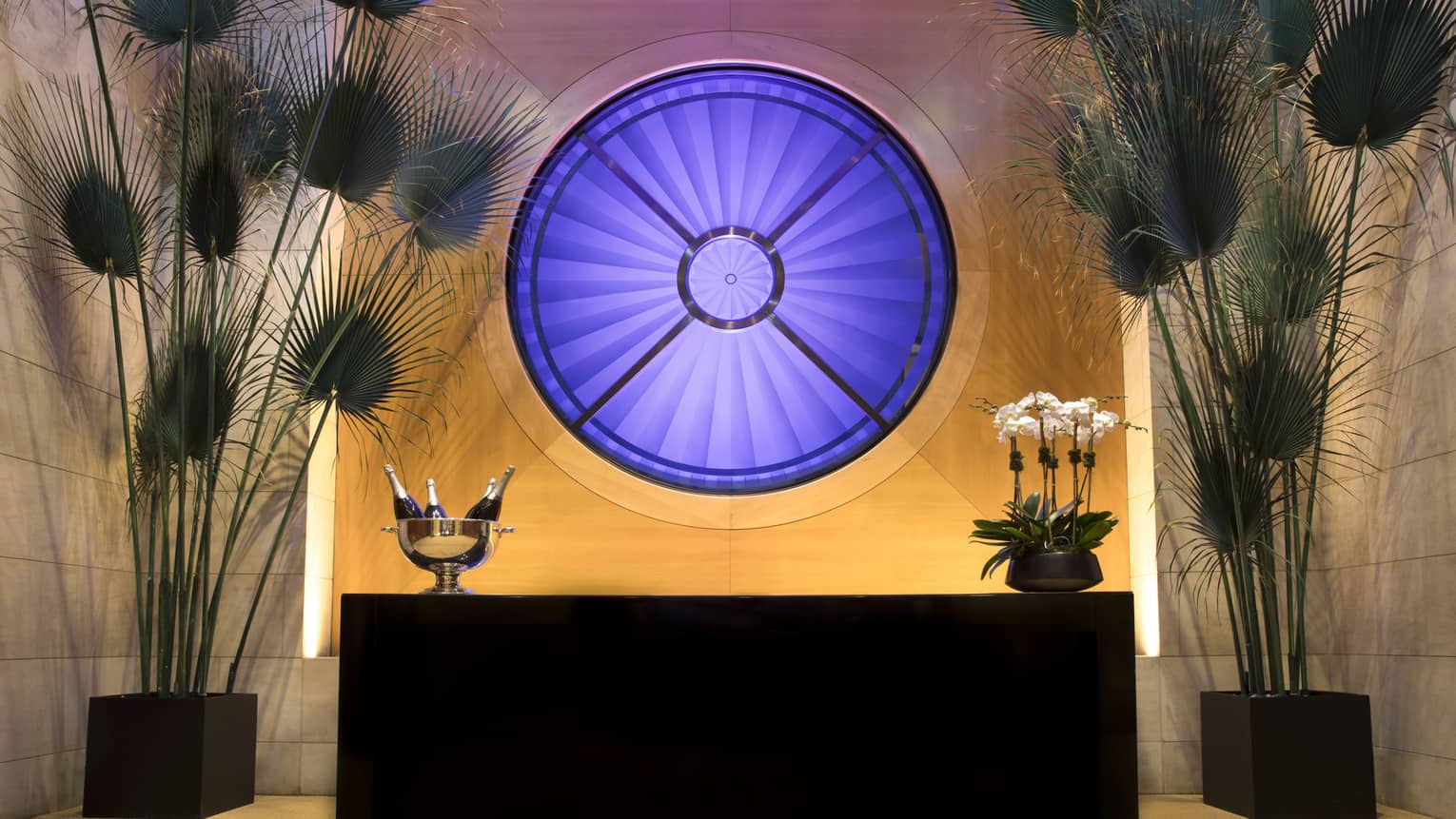 Fifty7 Center round blue Oculus window over buffet table with Champagne, tall fan-shaped tropical plants