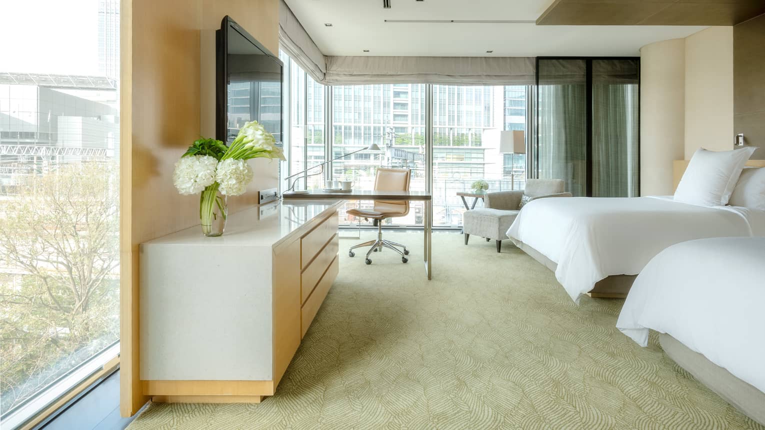 Deluxe Premier Twin Room with desk area and floor-to-ceiling corner windows looking out onto the city skyline