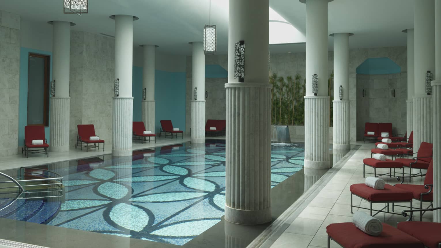 Tall white pillars around long indoor swimming pool