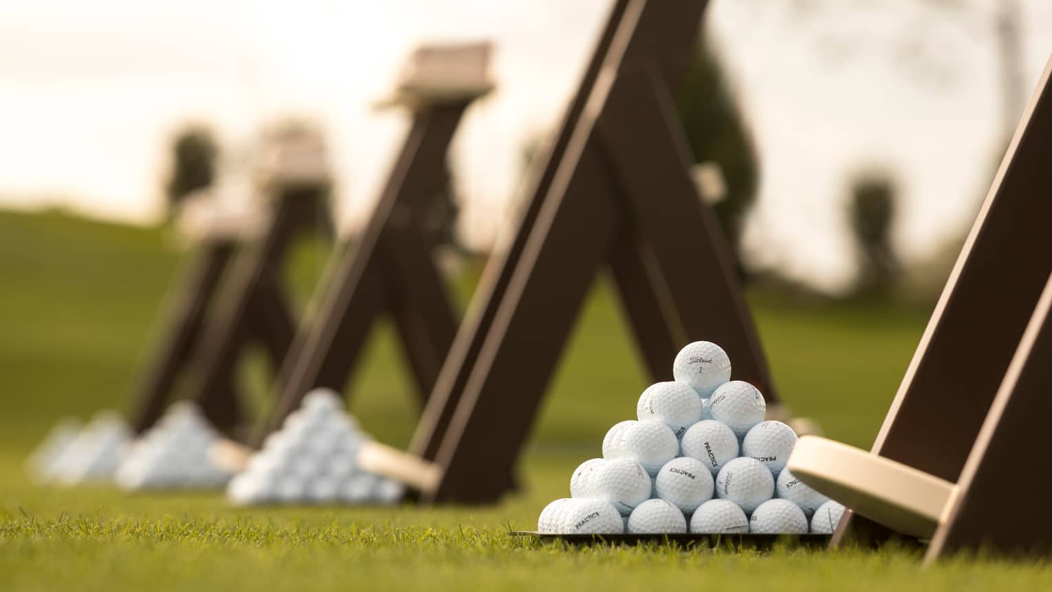 Stacks of white golf balls on lawn in front of wood panels