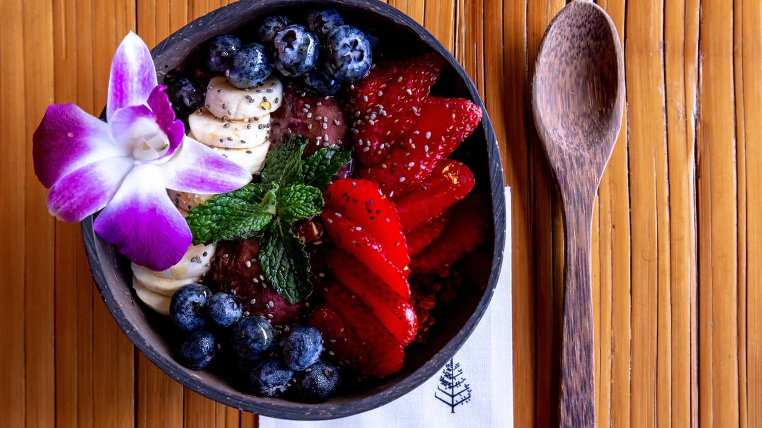 Acai bowl with strawberries, blueberries and a Hawaiian flower