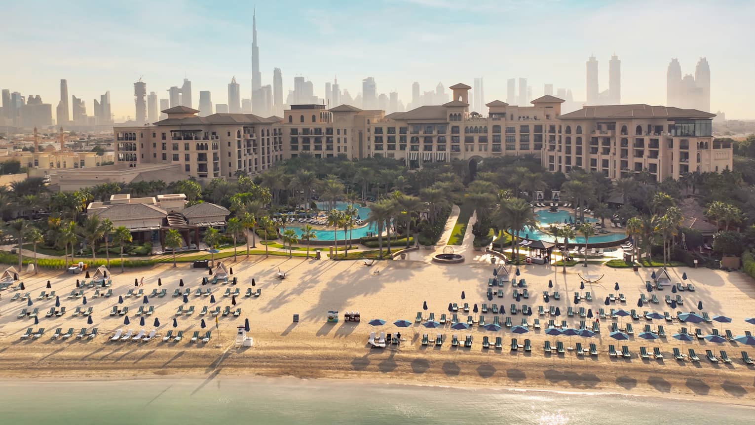 An overhead shot of a resort with lines of beach chairs in front of the bay.