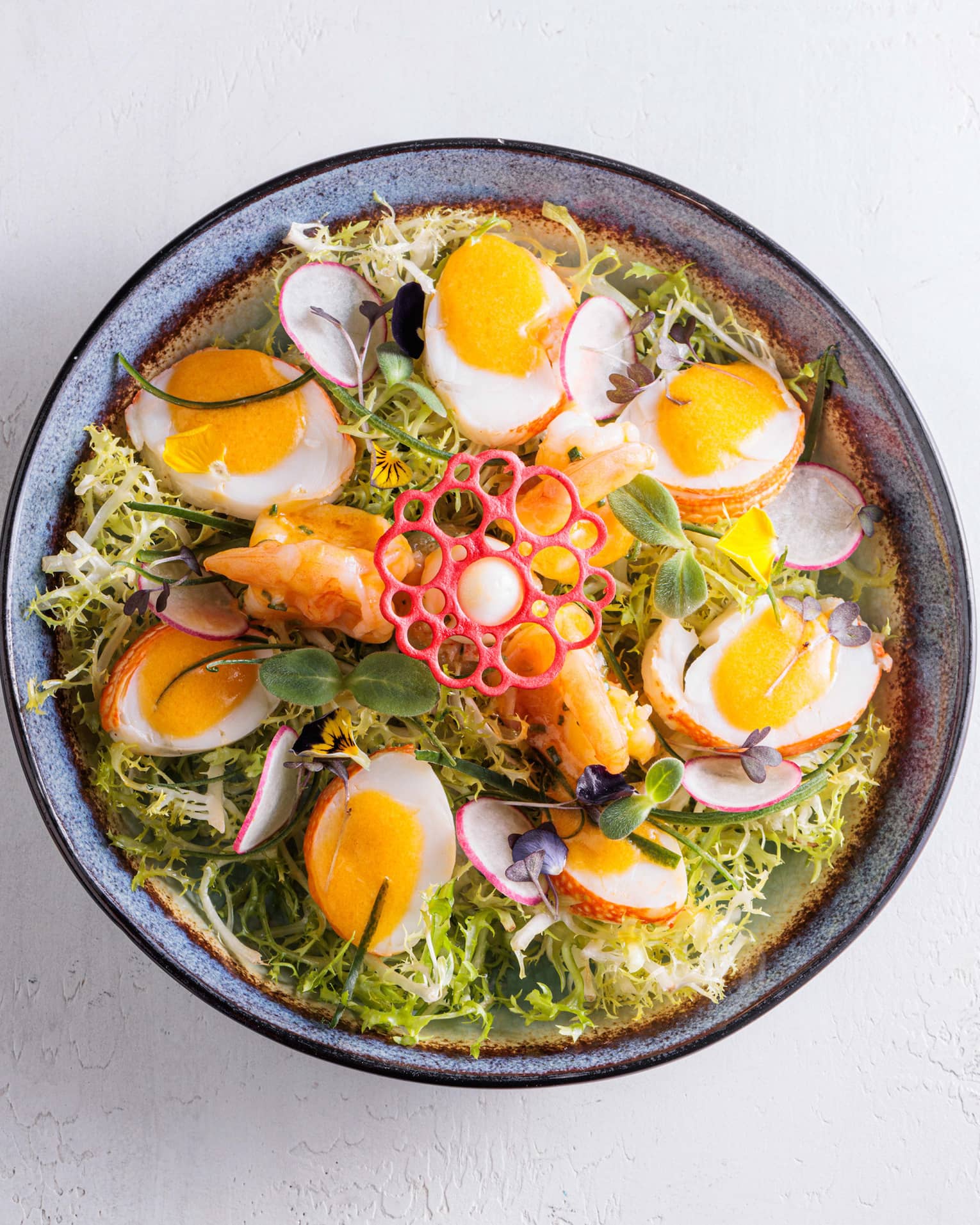 Bowl of greens, halved soft-boiled eggs, sliced radishes and a decorative garnish
