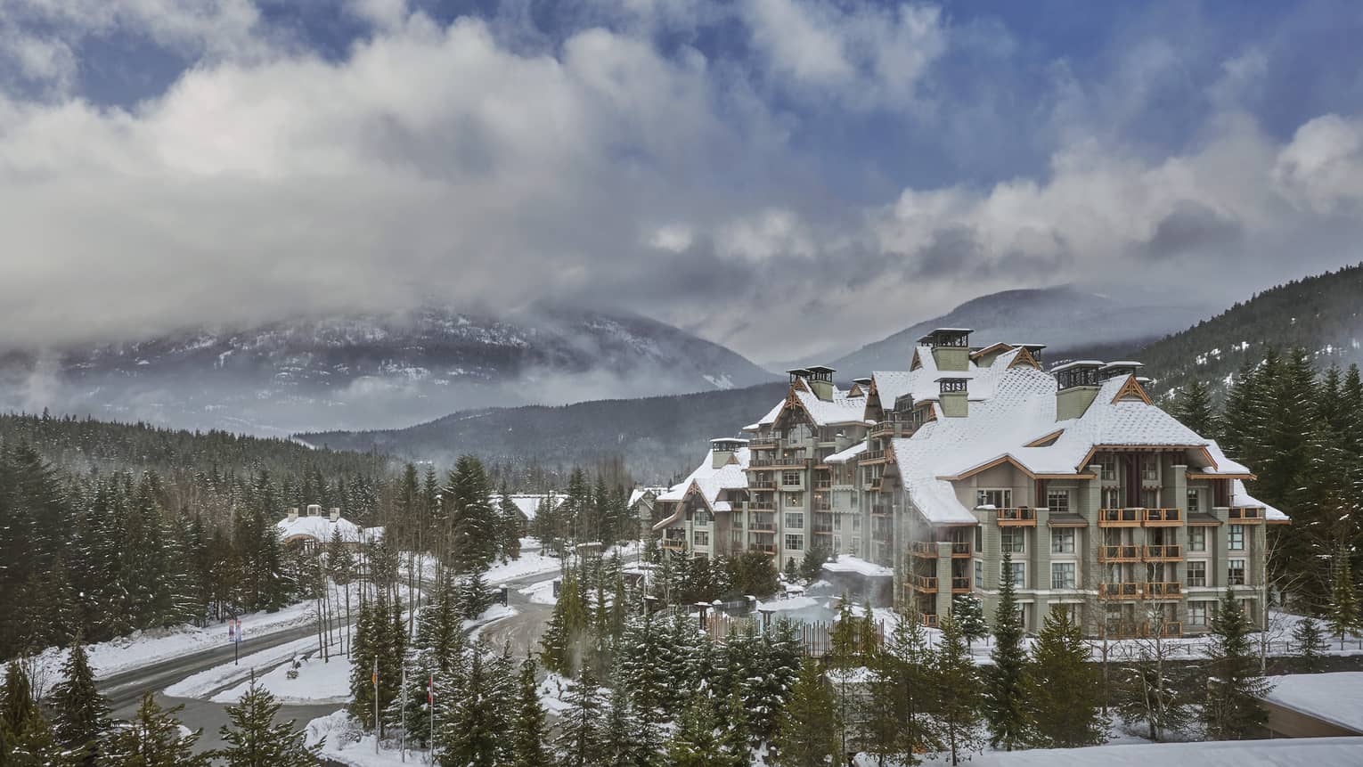 An external shot of FS Whistler covered in snow, with a large mountain behind. 